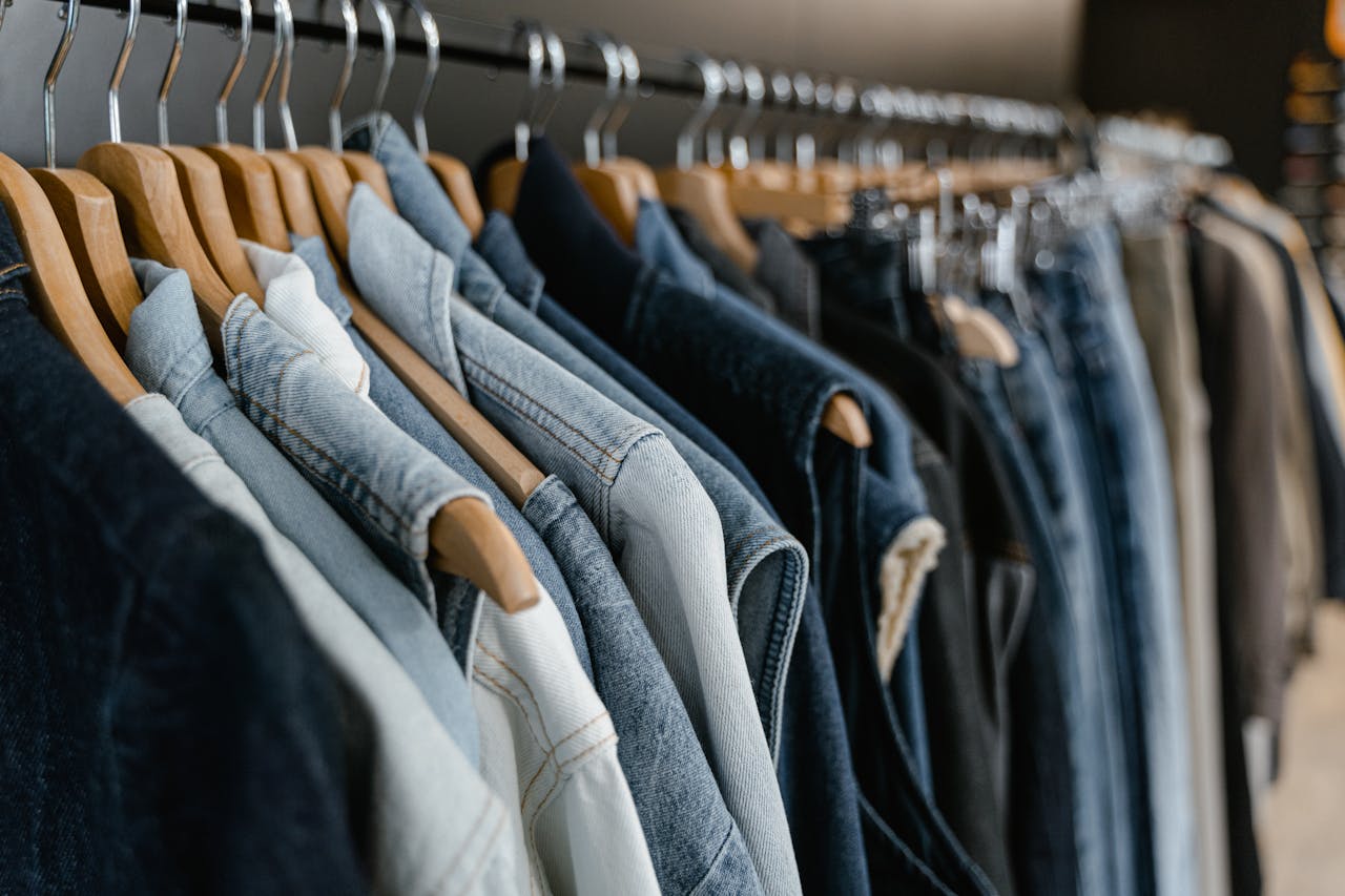 about-img-01 A close-up view of various denim jackets hanging on a clothes rack indoors.